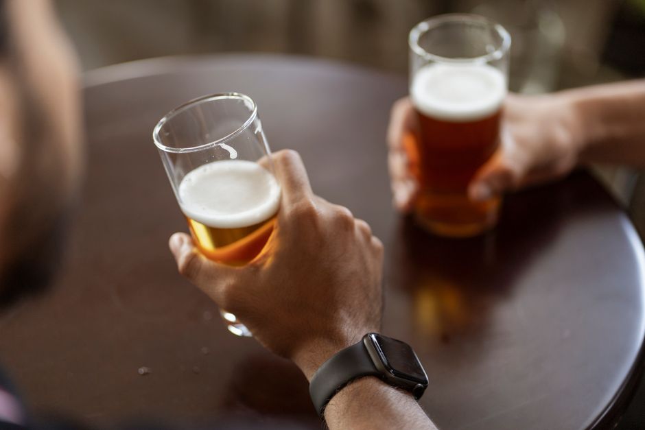 People at a backyard table enjoying glasses of assorted beers in different colors and styles.