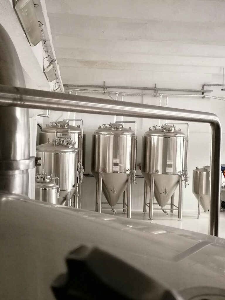 A person stirring a large pot of malted grain and water on a kitchen stove, preparing ingredients for beer brewing.