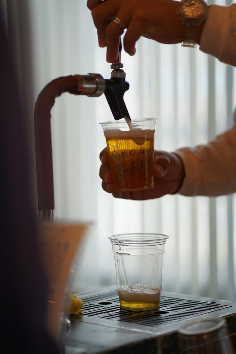 A person using a hydrometer to check the gravity of a beer sample in a kitchen or homebrew setting.