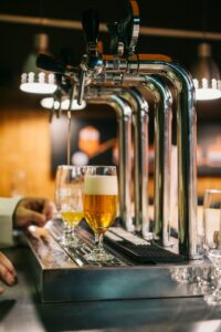 A person examines the color, foam, and aroma of beer poured into a clear tasting glass.