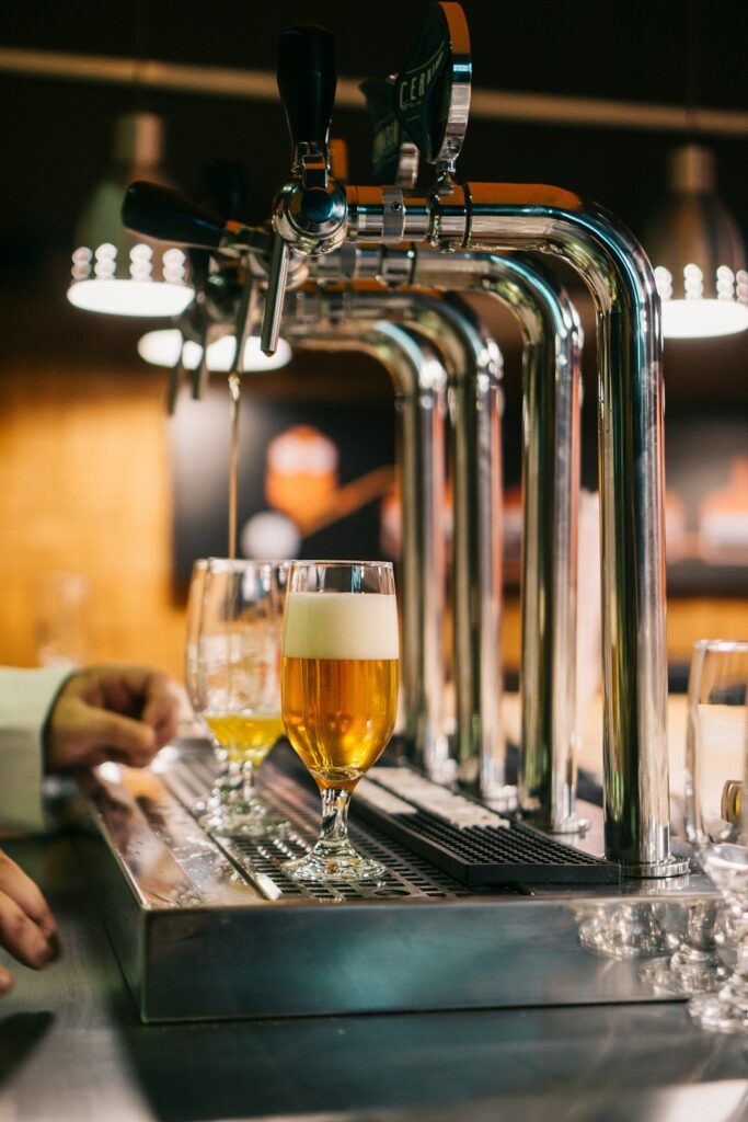 A person examines the color, foam, and aroma of beer poured into a clear tasting glass.